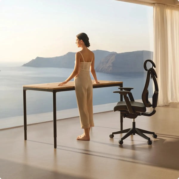 Woman standing at a Desktronic HomeMax four-leg desk by a large window