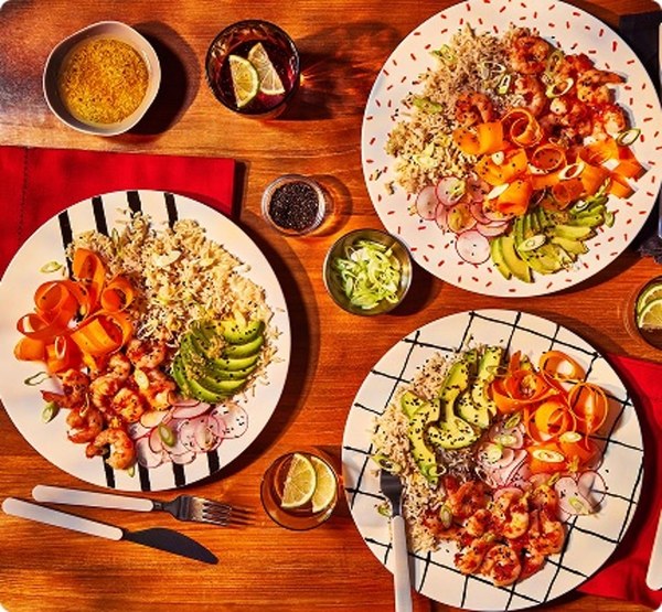 Colourful plates of cooked meals with rice, salad and avocado on a table