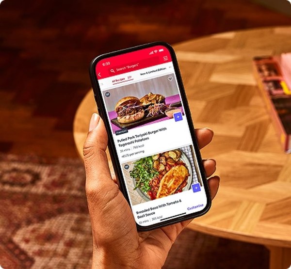 Hand holding a phone showing a recipe in the Gousto app