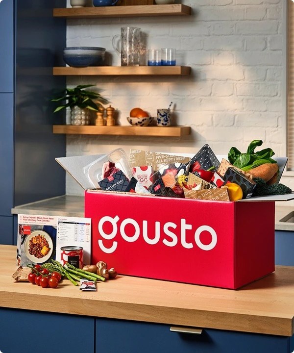 Open Gousto box on a kitchen worktop with fresh ingredients and meal packs