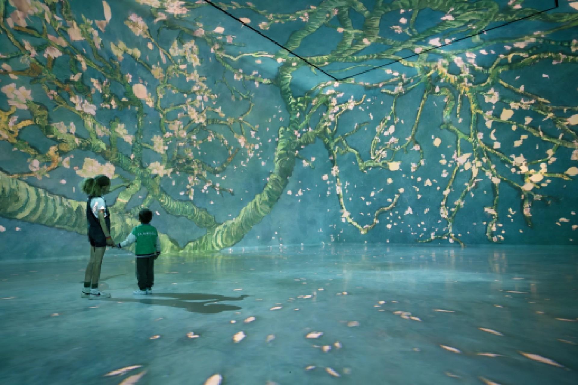 Visitors walking through a floor-to-ceiling projected painting in an immersive FRAMELESS gallery