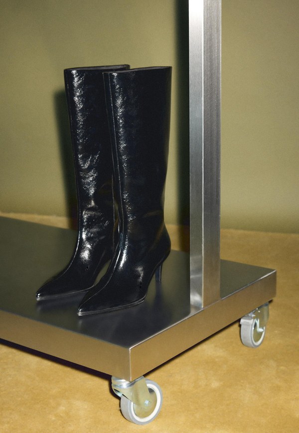 Pair of black knee-high boots displayed on a metal trolley, from the Stradivarius autumn collection