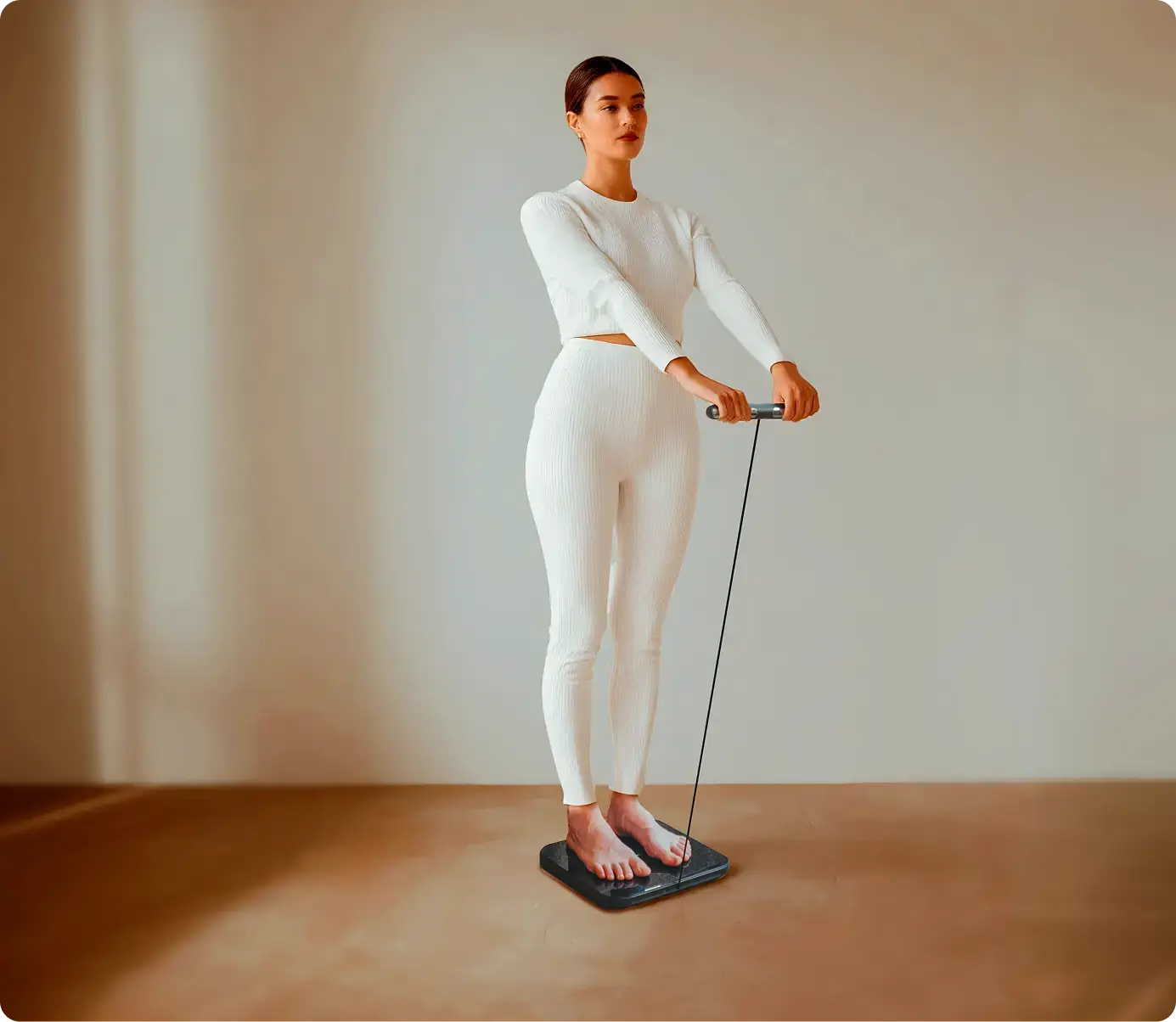 Woman standing on the Hume Pod scale holding the sensor handle for a full-body composition scan