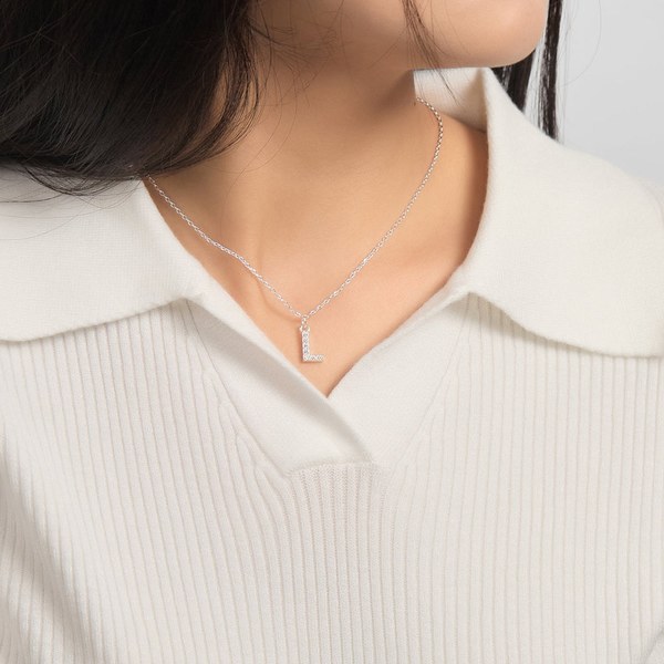 Woman in a white collared top wearing a pave initial necklace on a delicate chain