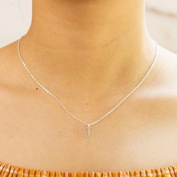 Woman wearing a fine sterling silver initial necklace with a small letter pendant