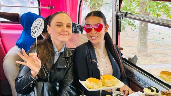 Two guests with props enjoying afternoon tea next to a bus window