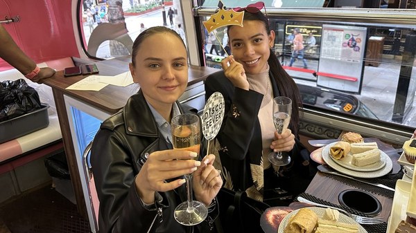 A guest holding a glass of prosecco beside a plate of sandwiches on the upper deck