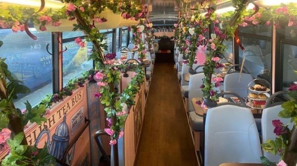 The upper deck of a London bus decorated with flowers along the ceiling and windows