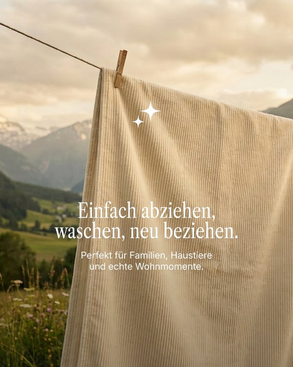 Removable beige sofa cover hanging on a washing line with mountains behind, from a Livom campaign image