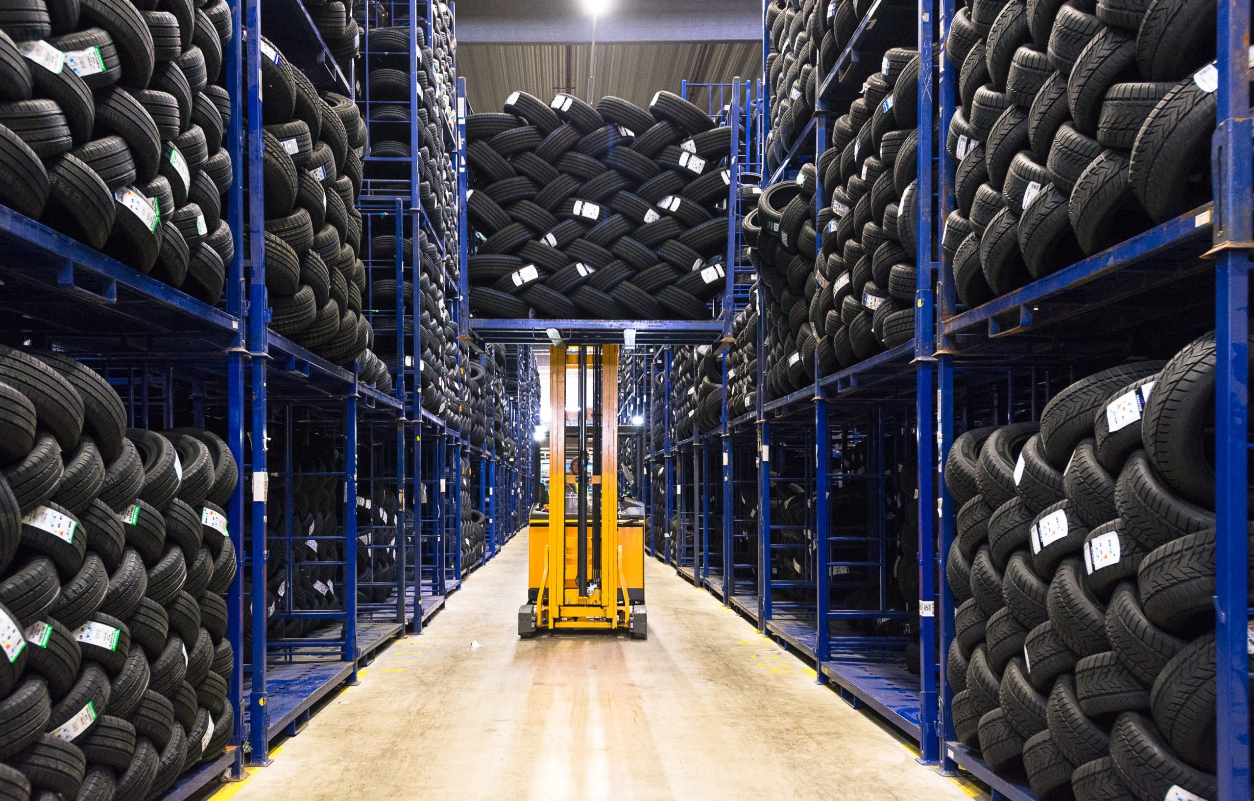 Tyre warehouse aisle stacked with thousands of tyres