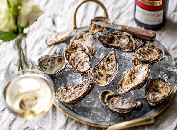 Wright Brothers oyster gift box with a dozen oysters on ice beside a bottle of champagne